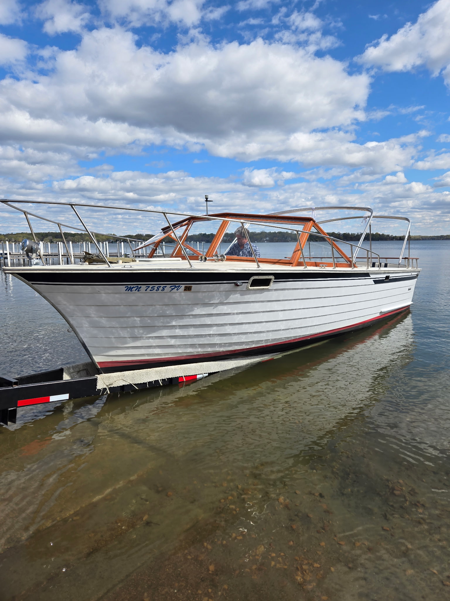 Classic boat being launched at a Minnesota lake ramp on a sunny day.